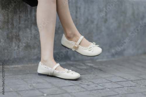 Woman wearing fashionable cream mary jane shoes with bows and lace details