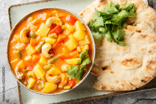 Creamy vegetable vegan korma featuring vibrant vegetables closeup on the bowl on the table. Horizontal top view from above