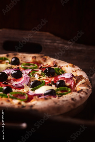 Pizza with chorizo ​​sausage, mozzarella cheese and green pepper. Rustic wooden background. Soft focus.