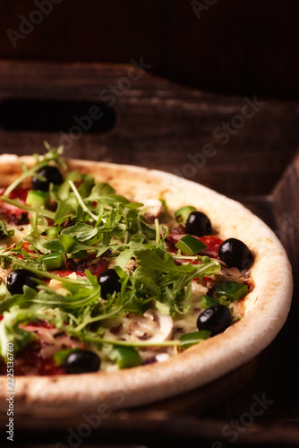 Pizza with chorizo ​​sausage, mozzarella cheese and green pepper. Rustic wooden background. Soft focus.