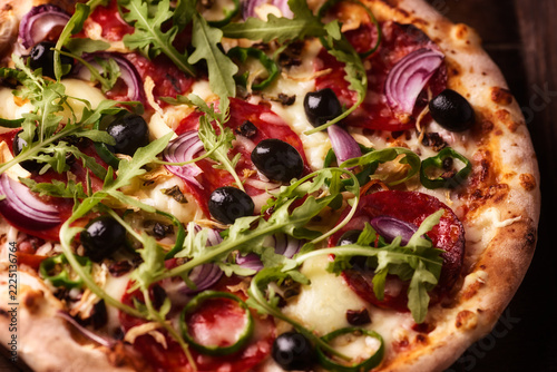 Pizza with chorizo ​​sausage, mozzarella cheese and green pepper. Rustic wooden background. Soft focus.