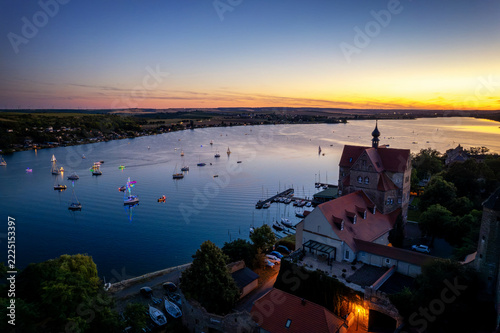 Viele Segelboote auf einem See neben einem Schloss bei Sonnenuntergang
