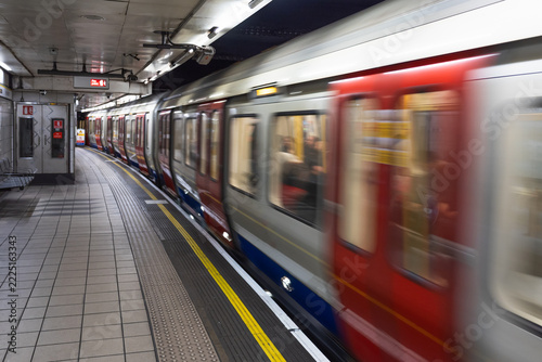 Subway train moving along a curved underground station platform