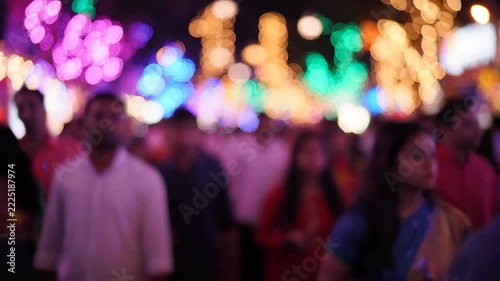Vibrant bokeh lights illuminate a bustling, blurred crowd at a festive night event.