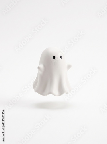 Cute matte white ghost figurine with raised arms floating on light background, vertical Halloween decor