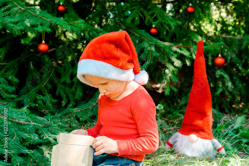 Child kid waiting for Christmas.little boy opening gift box near fir tree.winter festive holidays,family.Merry Christmas eve,New Year,Happy Holidays