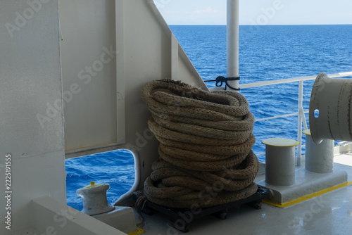 Coiled mooring rope resting on the open deck of a ship sailing through deep blue sea waters in Rhodes, Greece.