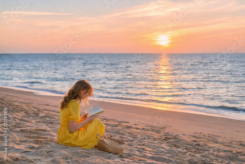Young Woman Reading Book on Beach at Sunset