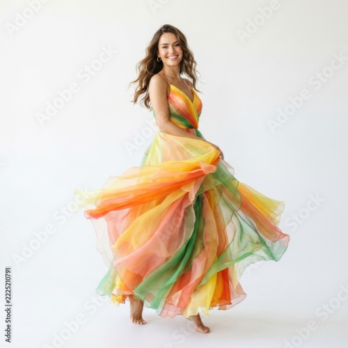 Happy young woman in a colorful long dress dancing and spinning around with a joyful smile isolated on white background