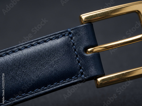 Close-up of blue leather belt with gold buckle and stitching