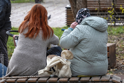 Women sit with a child on a park bench on an autumn day