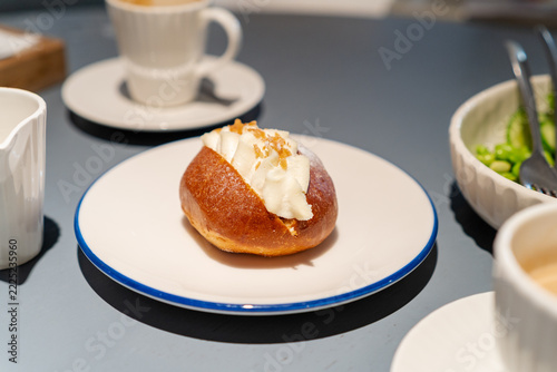 Sweet cream bun dessert on white plate at cafe table