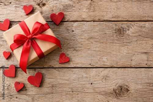 Gift box and red wooden hearts on a rustic plank love background