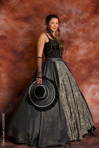 Elegant woman posing in in 19th-century Victorian gown and black hat