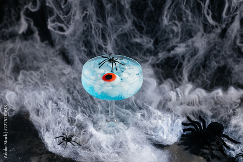 Halloween blue cocktail with eyeball and spiders on cobwebs