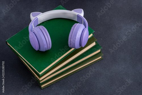 Study background Wireless Headphones with Cat Ears on Stack of Hardcover Books Top View.