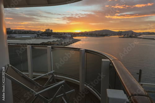 Pooldeck or swimmingpool with sun deck on modern cruiseship cruise ship liner in port with sun loungers ready for cruising to Mediterranean on sunny day with city skyline in background