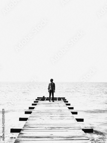 man standing on a wooden pier facing the sea with halftone pattern