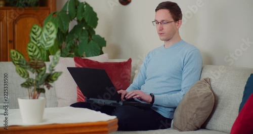 Man working on laptop on a sofa at home