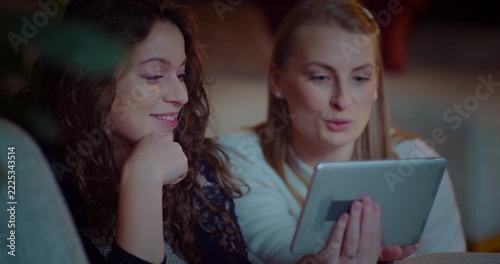 Two women sharing a tablet in a cozy indoor setting