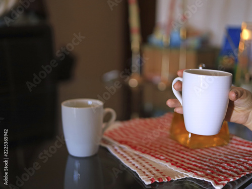 Hand holding a white mug, ceramic drinkware and tableware in home beverage service and everyday refreshment