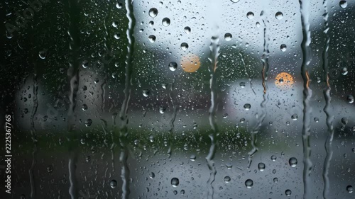 Raindrops cling to a window pane with blurred city lights in the background.