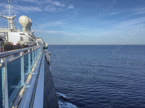 Pooldeck or swimmingpool with sun deck on modern cruiseship cruise ship liner in port with sun loungers ready for cruising to Mediterranean on sunny day with city skyline in background