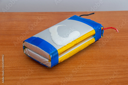 Swollen Lithium-ion battery on wooden table.