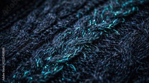 Macro close-up of dark knitted woolen fabric woven with glowing turquoise fiber optic threads representing data weaving concept