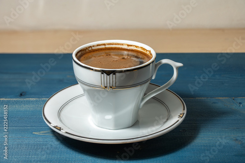 Cup of black coffee on blue wooden table.