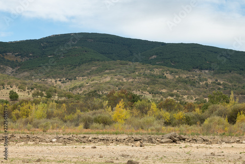 Reservoir with low water level during drought in autumn mountains