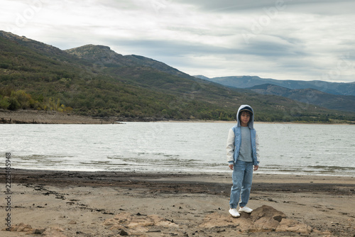 Boy standing on reservoir shore with low water level in Spain