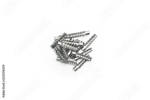 Pile of serrated metal expansion inserts on white