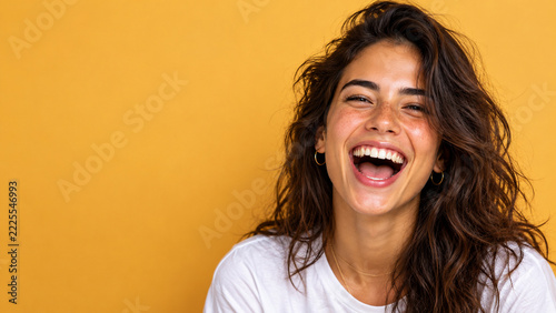 Happy Young Woman Laughing Against a Mustard Yellow Background