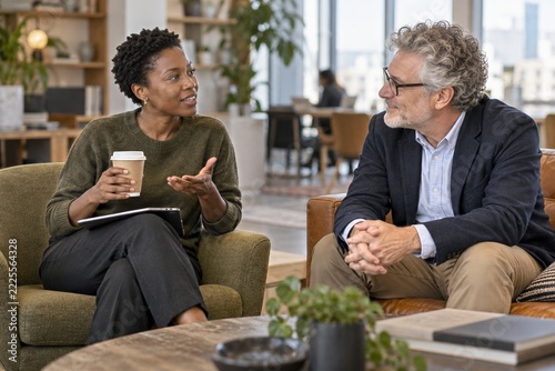 Short haired woman talking over takeaway coffee with a seated colleague