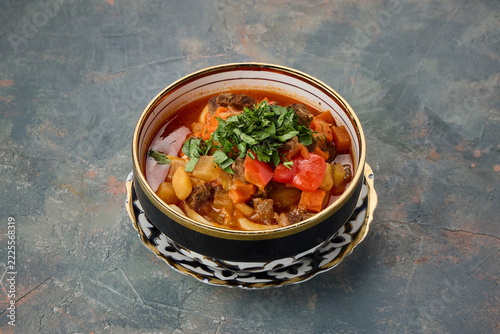 A bowl of vegetable soup garnished with fresh herbs on a decorative