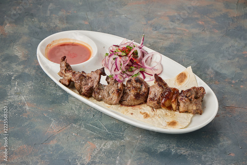 Grilled meat skewers served with onion salad and dipping sauce