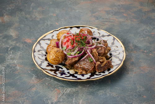 A plate of grilled meat served with potatoes and garnished with sliced