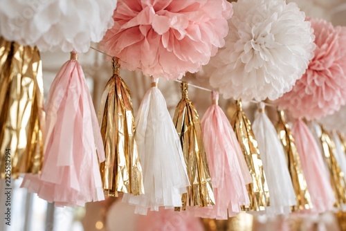 Pink white and metallic gold tassels beneath fluffy paper decorations