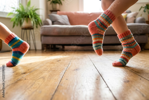Children in colorful socks running across a wooden living room floor, low-angle motion view