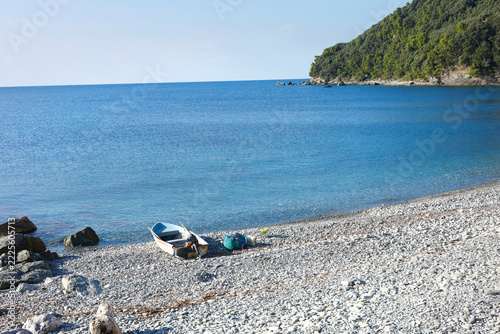 Fishing boat pebble beach Riva Trigoso Italy. Summer serenity coastal lifestyle sea tranquility. Mediterranean travel destination maritime story guide.