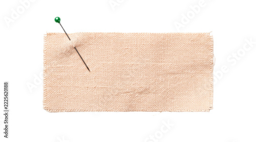 A vibrant green-headed sewing pin piercing a rectangular piece of textured beige fabric, isolated on a clean white background, symbolizing crafts, textile work, and creative projects