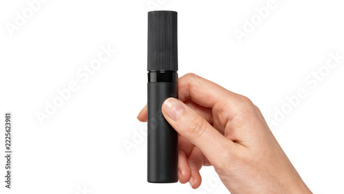 Hand holding a cylindrical black atomizer with ribbed cap during product photography