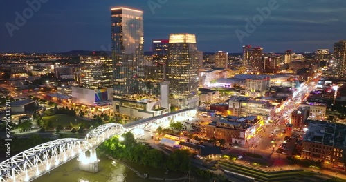 Nashville city urban environment in Tennessee, USA at night. View from above of skyscraper district with riverfront bridge in evening atmosphere.