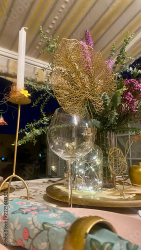 Crystal wine glass close up on elegant festive table with glowing fairy lights bokeh