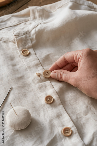 Replacement button held beside a stitch remnant on a shirt placket