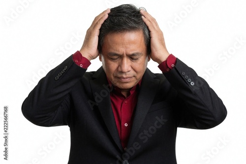 Stressed Indonesian businessman in black suit, red shirt holds head with both hands. Middle aged male professional feels headache, frustration burnout. Worried man expresses mental health crisis,