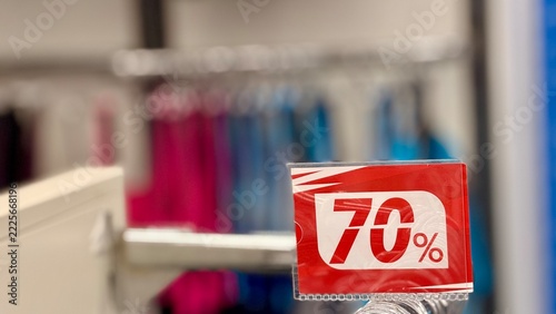 Fotografie Close-up of a red “70%” discount sign attached to a clothes rack arm in a clothing store