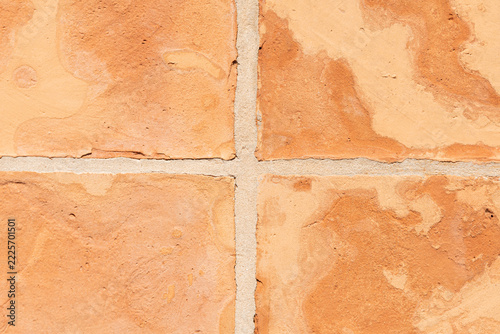 Terracotta clay tiles forming a textured wall patterns with visible grout lines