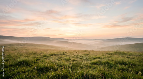 A serene landscape of rolling hills and green grass at sunrise or sunset with a misty atmosphere